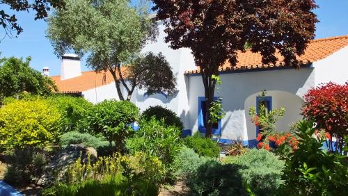 a white house with a garden in front of it at Monte Alerta Turismo Rural in Monsaraz