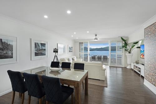 un soggiorno con tavolo, sedie e divano di Frangipani Beachfront Lodge 202 on Hamilton Island by HamoRent a Hamilton Island