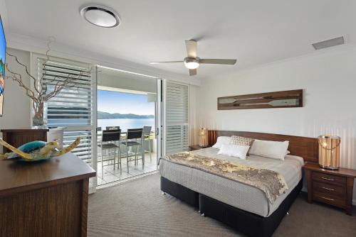 una camera da letto con un letto e vista sull'oceano di Frangipani Beachfront Lodge 202 on Hamilton Island by HamoRent a Hamilton Island