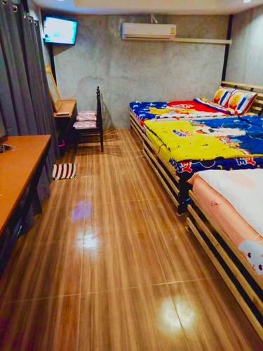 a bedroom with two twin beds and a television at บ้านเดอะเมาเท่น By The Mountain Ozoneบ้านโอโซนขุนเขาแก่งกระจาน in Ban Song Phi Nong