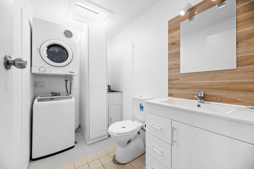 uma casa de banho branca com um WC e um lavatório em The Harrington Serviced Apartments em Narooma