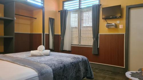 a bedroom with a bed and a window and a television at Dewi Sri Guesthouse in Mataram