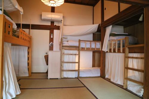um quarto com 3 beliches e um lustre em Guest House Kamejikan em Kamakura