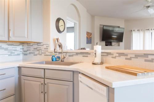 a kitchen with white cabinets and a sink and a tv at Gated Ocotillo Townhouse with heated pool, spa, BBQ in Chandler