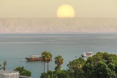 two boats in the water with the sun in the background at Luxury Apartment on the Lake in Tiberias