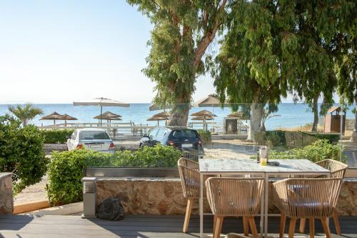 einen Tisch und Stühle mit Blick auf den Strand in der Unterkunft Seasabelle Hotel near Athens Airport in Artemida