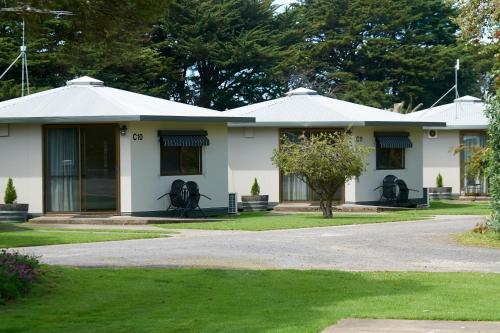 a white house with windows and a grass yard at Pine Country Caravan Park in Mount Gambier