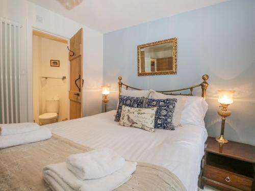 - une chambre dotée d'un lit blanc avec deux lampes et un miroir dans l'établissement 1 Sunny Point Cottages, à Kendal