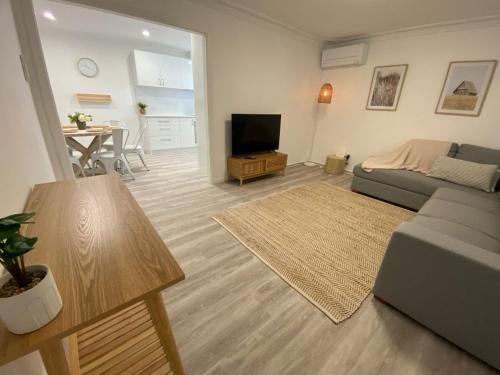 a living room with a couch and a television at Peppermint Cottage in Broadwater