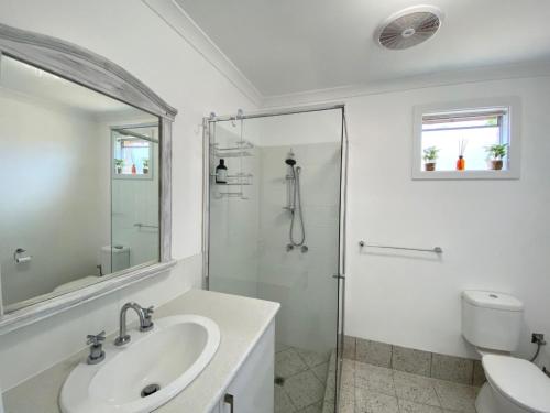 uma casa de banho branca com um chuveiro e um lavatório. em Peppermint Cottage em Broadwater