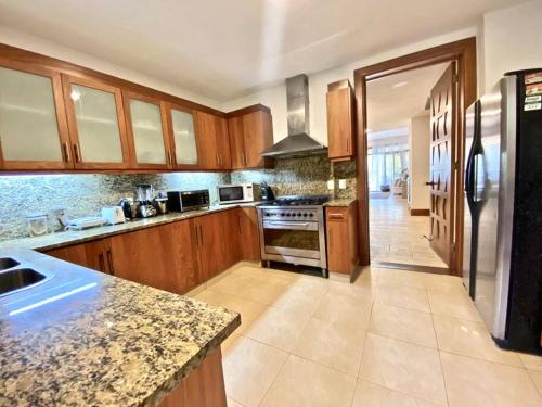 a large kitchen with wooden cabinets and a refrigerator at Chic Luxury Condo At Los Altos Casa De Campo in La Romana
