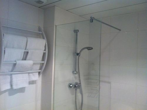 La salle de bains est pourvue d'une douche et de serviettes murales. dans l'établissement Vichy Résidencia, à Vichy