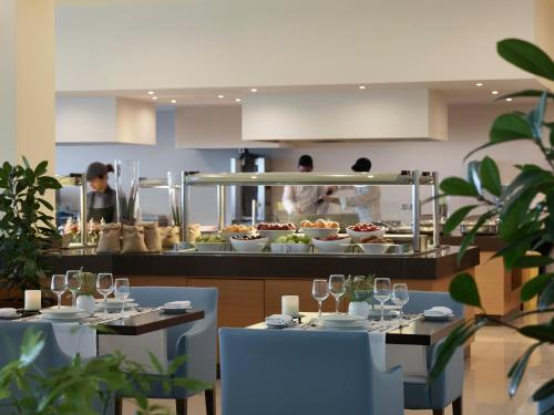 a restaurant with two tables and two chefs in the kitchen at Apollo Blue in Faliraki