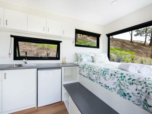a small kitchen and bed in a tiny house at Burroo at Kangaroo Valley I Perfect Views I Outdoor Bath in Barrengarry