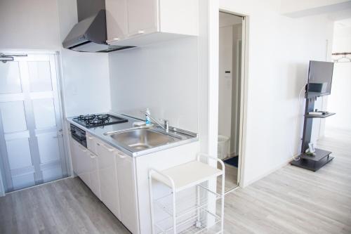 a white kitchen with a sink and a stove at パークサイドモリ in Motobu
