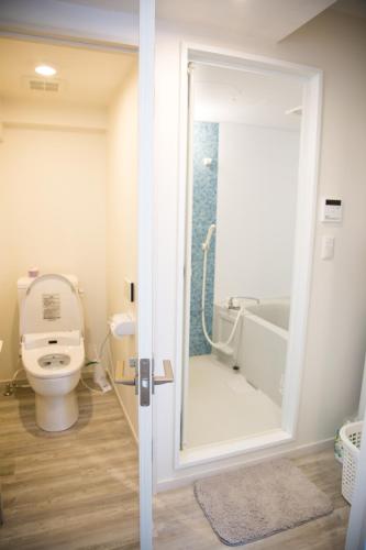 a bathroom with a toilet and a tub and a shower at パークサイドモリ in Motobu