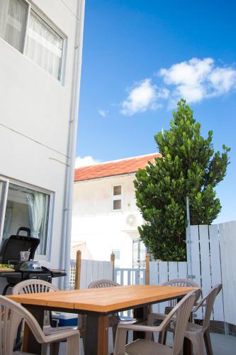 a wooden table and chairs on a patio with a tree at パークサイドモリ in Motobu