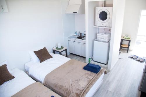 a small bedroom with two beds and a microwave at パークサイドモリ in Motobu
