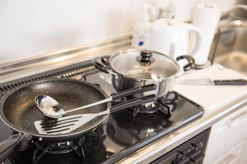 a pan on the stove with a spoon and spatula at パークサイドモリ in Motobu