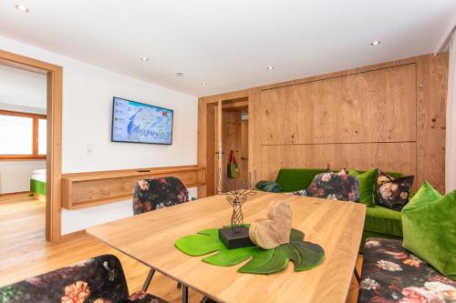 a living room with a table and a green couch at Wanderhotel Kirchner in Bramberg am Wildkogel