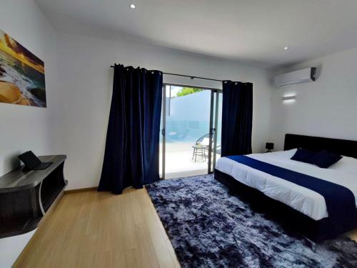 een slaapkamer met een bed en een glazen schuifdeur bij Villa Cap Malheureux, piscine privée, salle de jeux in Petit Raffray