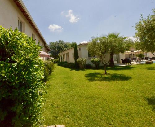 a green yard with a building and a tree at Hôtel Villa Sophia - ADULTS ONLY JULY AND AUGUST in Mougins