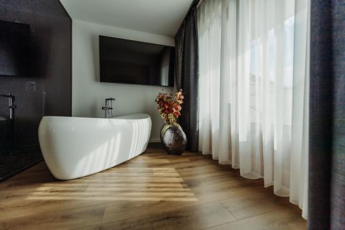 a bathroom with a large white tub and a vase with flowers at Boutique Damiani in Sibiu