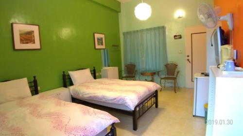 a green room with two beds and a table at 悦來民宿 台東縣民宿334號 in Taiping