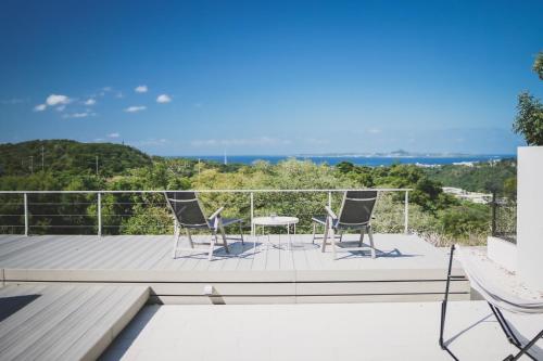 a deck with two chairs and a table on it at Motobu Terrace in Motobu