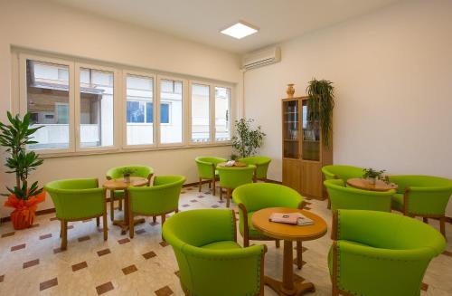 a waiting room with green chairs and tables at Villa Nazareth Fermo in Fermo