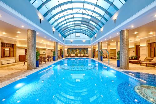 een zwembad in een hotel met een glazen plafond bij Premier Palace Hotel Kyiv in Kiev