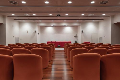 an empty lecture hall with orange chairs and a stage at Villa Nazareth Fermo in Fermo