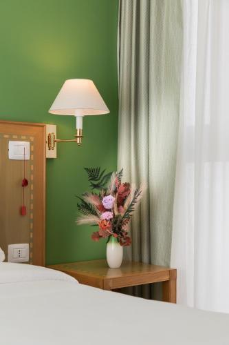 a vase of flowers on a table next to a bed at Villa Nazareth Fermo in Fermo
