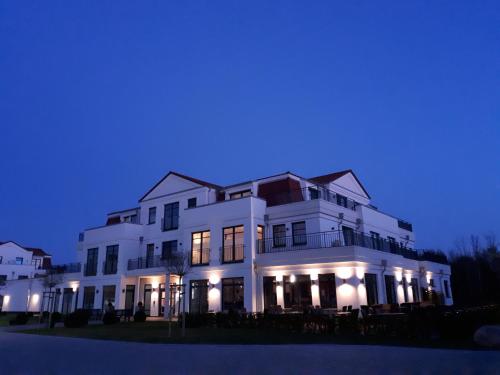 a large white house with lights on at night at Avalon Hotel Bellevue in Fehmarn