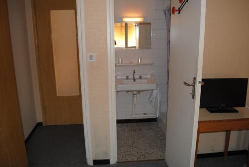 a bathroom with a sink and a computer on a desk at Le Logis Charmant in Charmes-sur-Rhône