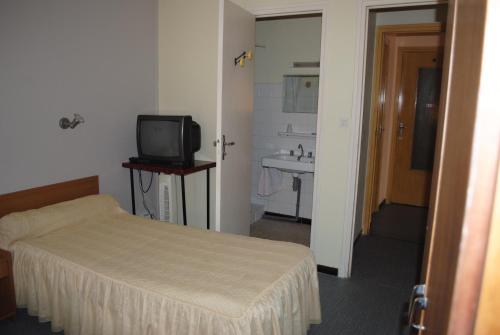 a small bedroom with a bed and a television at Le Logis Charmant in Charmes-sur-Rhône