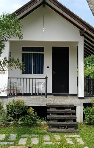 a small white house with a black door at The Anchorage Resort in Polonnaruwa