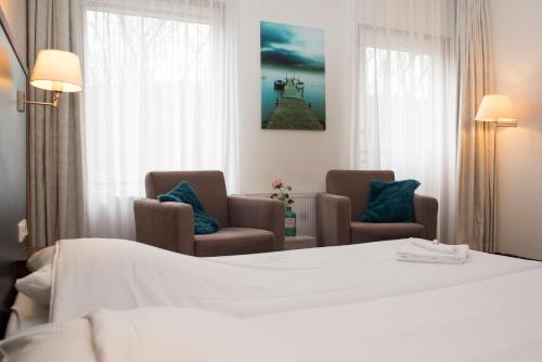 LoppersumにあるHotel Spoorzicht & SPAのベッド1台と椅子2脚が備わるホテルルームです。