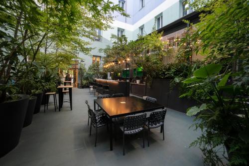 um restaurante com mesas, cadeiras e plantas em Petit Palace Santa Bárbara em Madrid