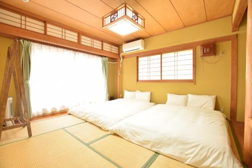 Duas camas num quarto com uma janela grande em Matoba 6F in Dotonbori em Osaka