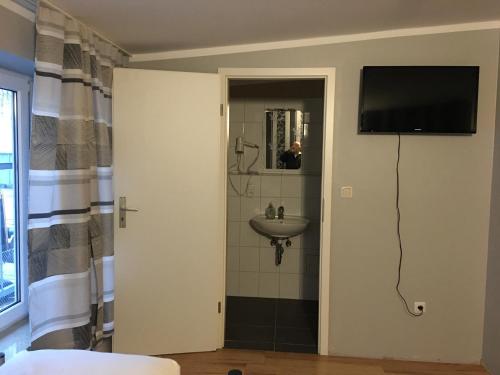 a bathroom with a sink and a television on a wall at Pension Alis Augsburg in Augsburg