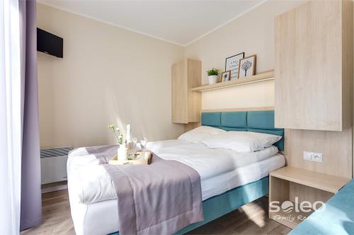 um quarto com uma cama branca e uma cabeceira azul em SOLEO Family Resort em Rewal