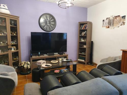 uma sala de estar com sofás e uma televisão e um relógio em Les colombes de l'Occitanie em Ferrals-lès-Corbières