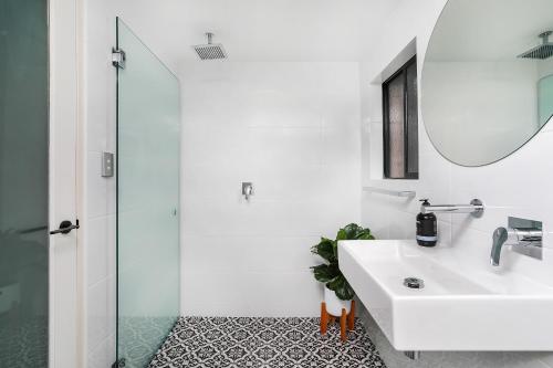 Baño blanco con lavabo y espejo en Spacious & Charming Alexandria 2 Bdrm Apartment - Secured Parking Space, en Sídney
