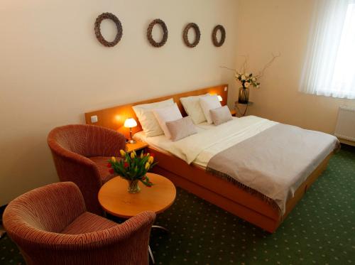 Schlafzimmer mit einem Bett mit 2 Stühlen und einem Tisch in der Unterkunft Hotel GIP in Grosspetersdorf