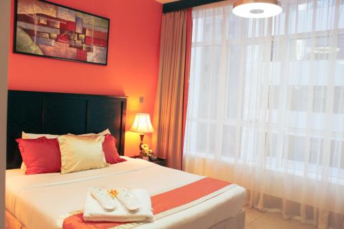 a bedroom with a bed with red walls and a window at Al Diar Sawa Hotel Apartments in Abu Dhabi