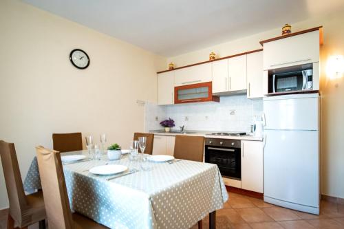 eine Küche mit einem Tisch und einem weißen Kühlschrank in der Unterkunft Kastell Apartments in Lopar
