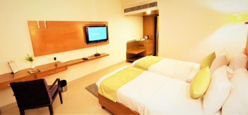 a bedroom with a bed and a flat screen tv at Gis Select Banjara Hill in Hyderabad