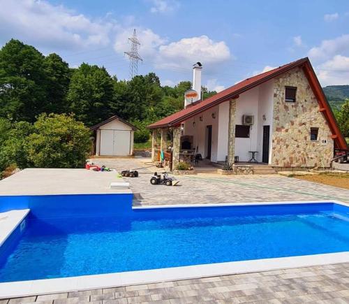 a house with a swimming pool in front of a building at Srce Kozare in Prijedor