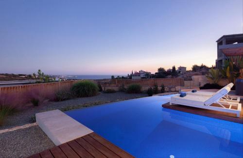 a swimming pool with a couch and a chair next to it at White Pearl in Paphos City